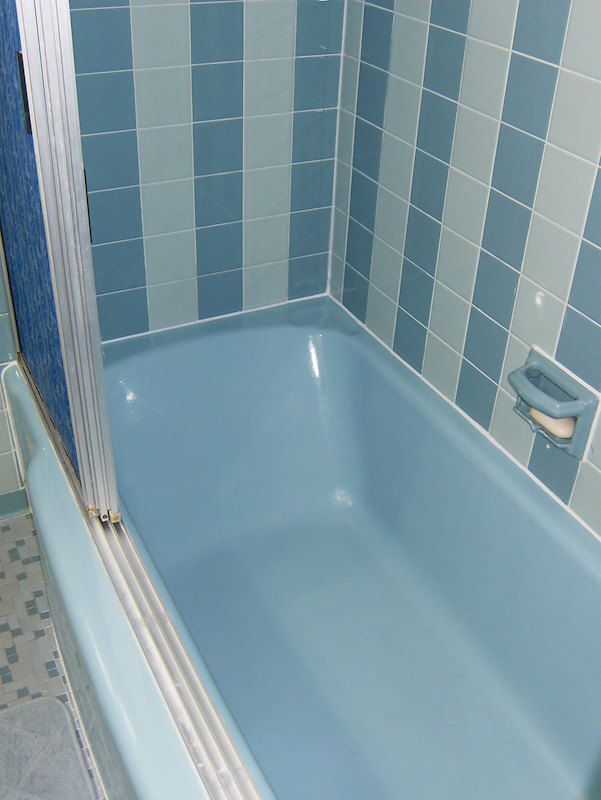 a blue bath tub sitting next to a tiled wall