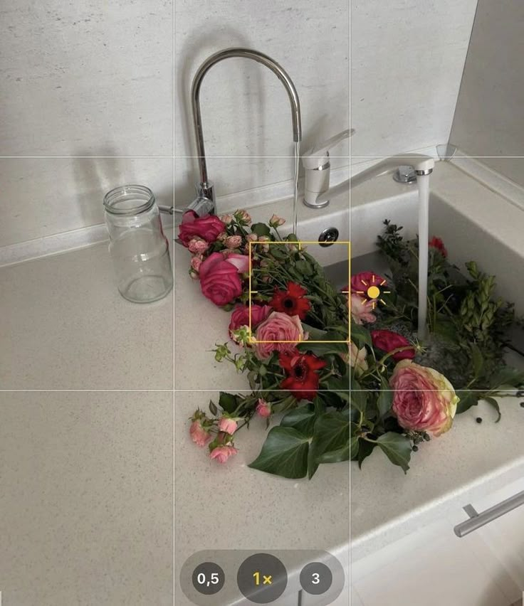 a sink with flowers on it and a glass jar next to it