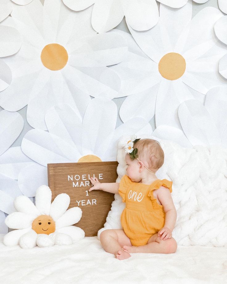 a baby is sitting on a bed and holding a sign