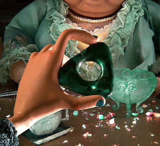 a close up of a person holding a green object in front of a table with confetti on it