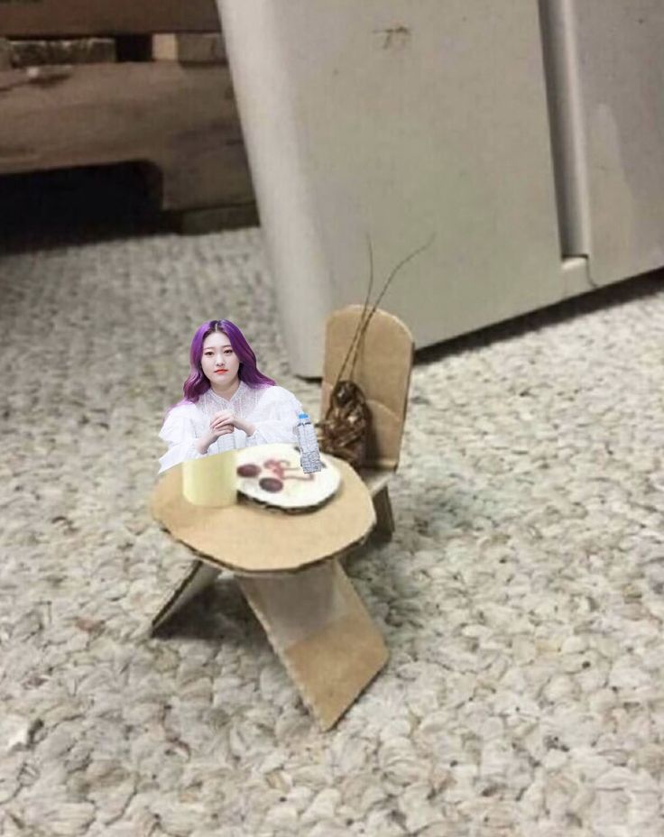 a doll sitting at a table with a plate of food in front of her on the floor