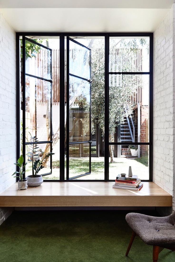 an open window in a white brick wall with books and plants on the table next to it