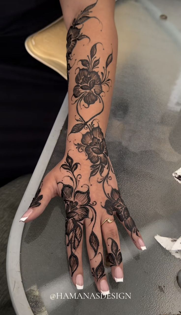 a woman's hand with tattoos on it and flowers on the wrist is shown