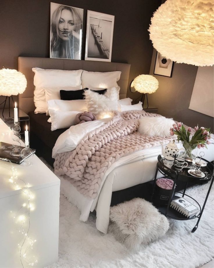 a bedroom with white bedding and lights on the headboard, two pictures above the bed