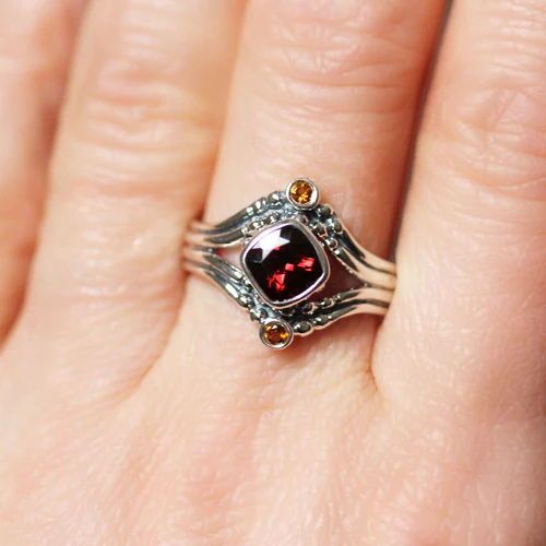 The Fire ring combines deep red garnet and lively citrines in a combination that is show-stopping! I sculpted this ring to represent flames of heat, light, and raw power. The Fire ring is part of my Elements collection and features a gorgeous genuine cushion cut red garnet and two honey colored sparkling citrines. #sterlingsilverring #garnetring #citrinering #statementring Garnet Stone Ring, Sacred Geometry Patterns, Fire Ring, Aries Leo, Handmade Engagement Rings, Fire Signs, Ethical Brands, Eco Friendly Jewelry, Meaningful Jewelry