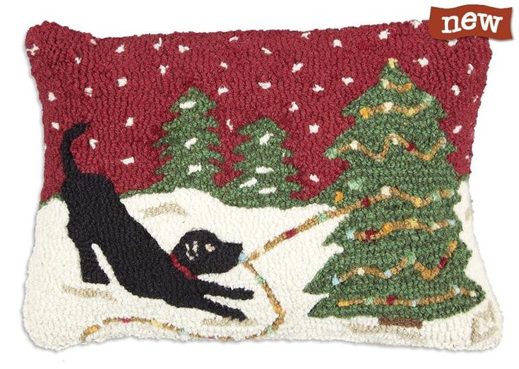 a black dog on a sled in front of a christmas tree hooked - up pillow