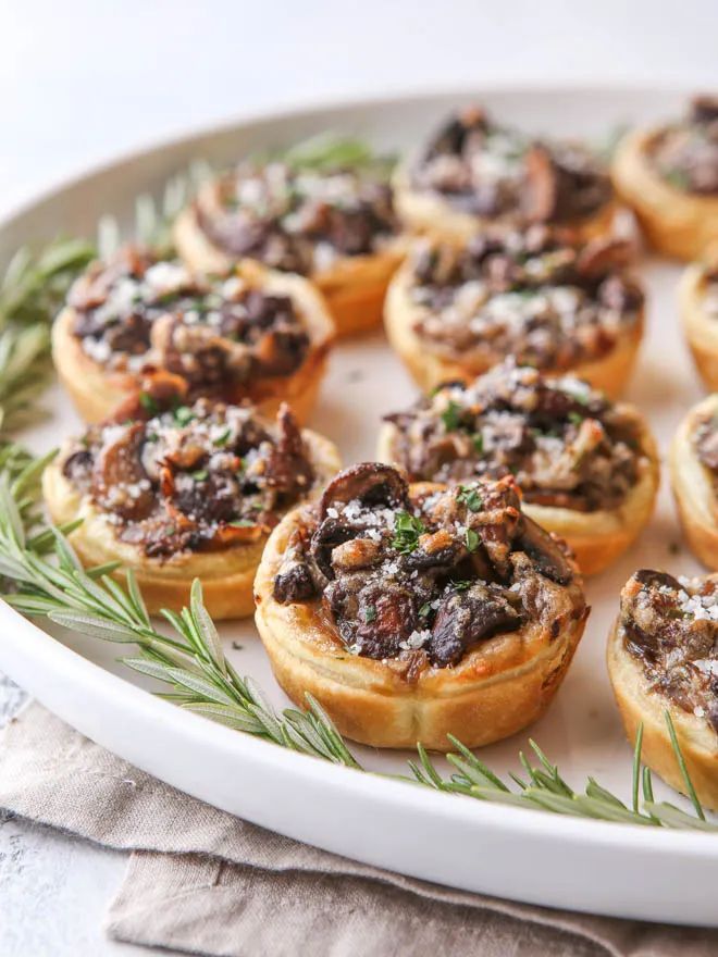 small appetizers are arranged on a platter with sprigs and rosemary