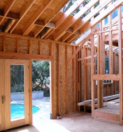 the inside of a house being built with wood framing on the walls and doors open