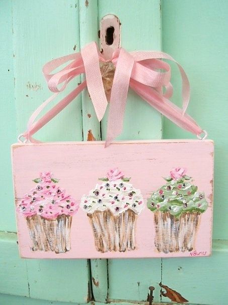 a pink sign with three cupcakes painted on it