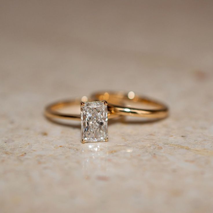 an engagement ring with a princess cut diamond in it sitting on a marble countertop