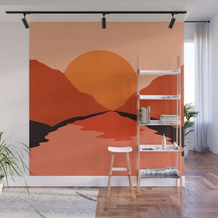 an orange sunset wall mural in a living room with a ladder to the right and bookshelves on either side