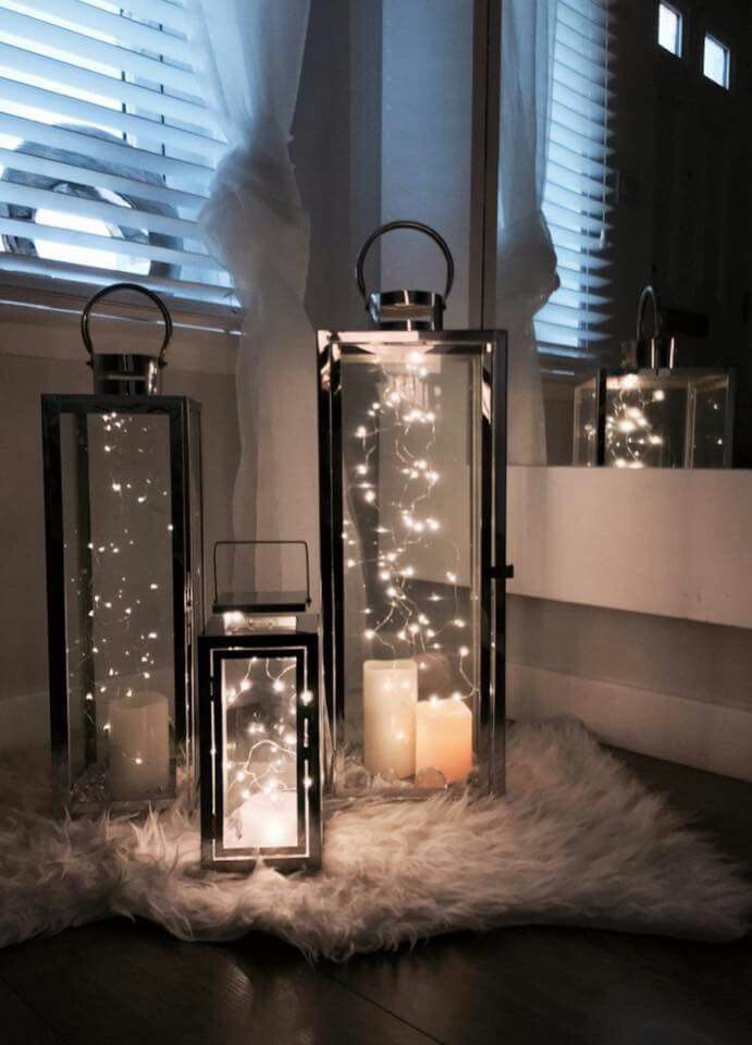 three lanterns are lit up on the floor in front of a window with white lights