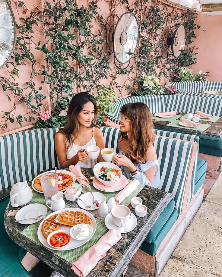 two women sitting at a table with plates of food