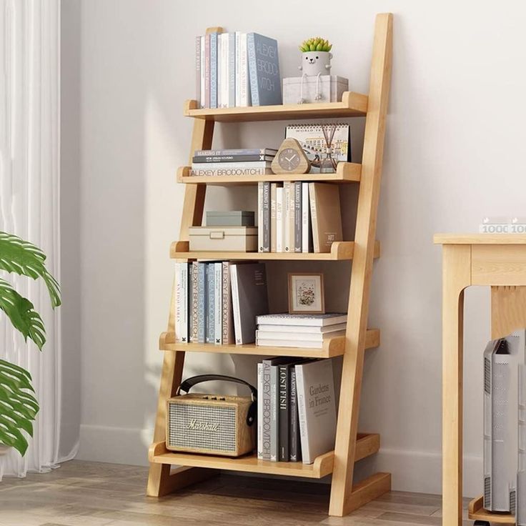 a bookshelf with many books on it next to a table and plant in the corner