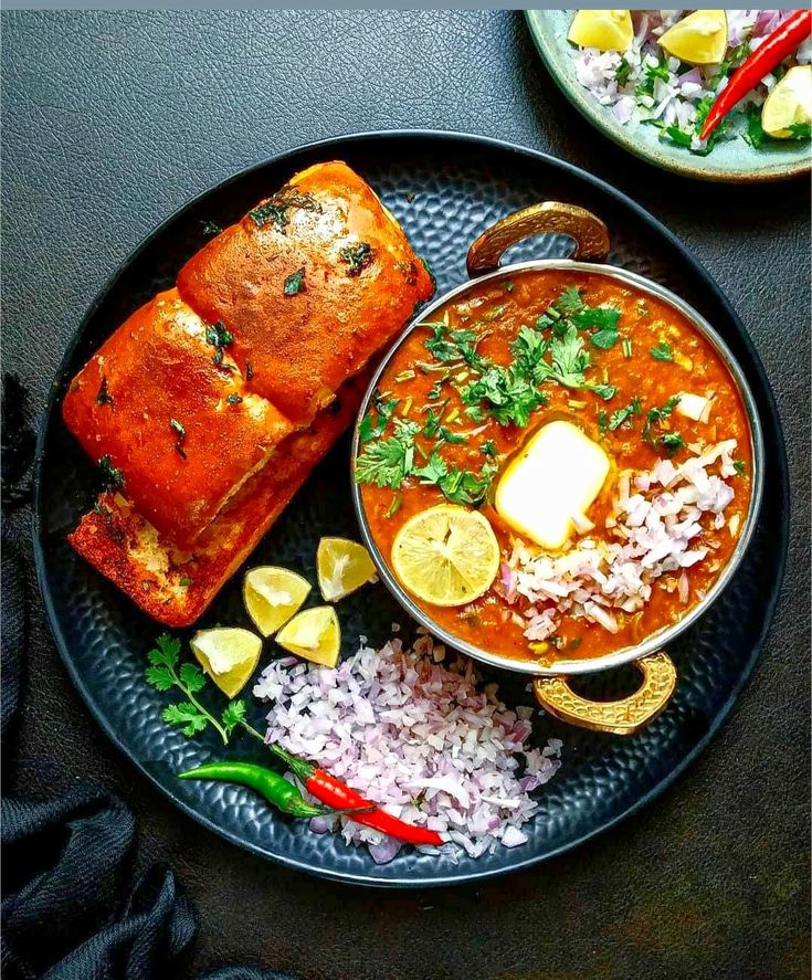 two plates filled with soup and bread on top of a black table next to rice