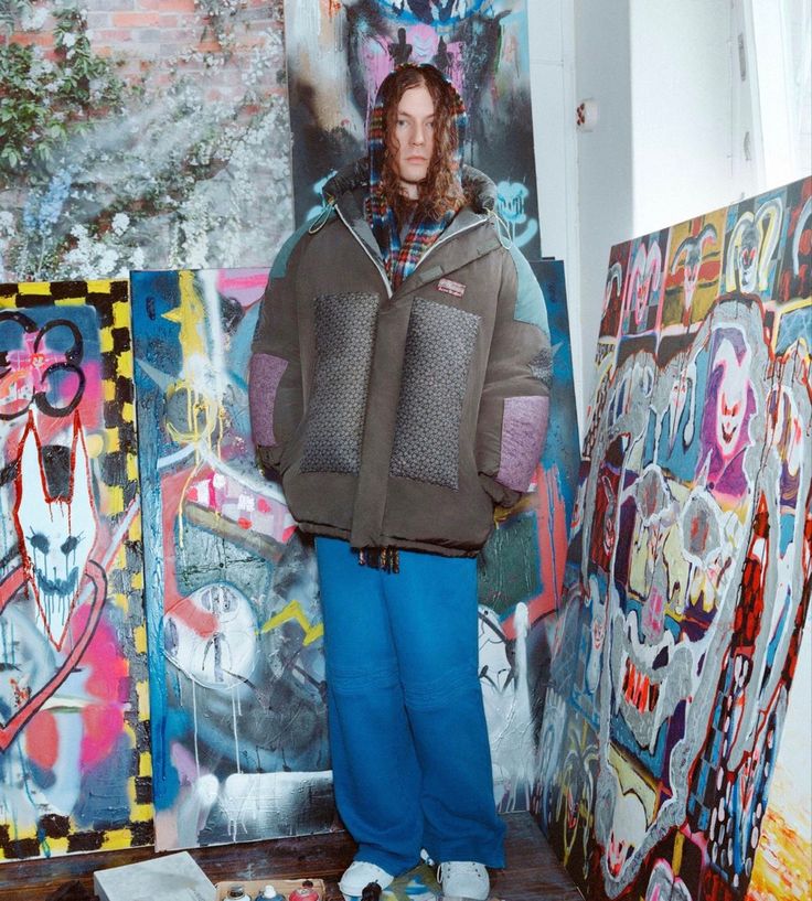 a man standing in front of some art work on the ground with his hands behind his back