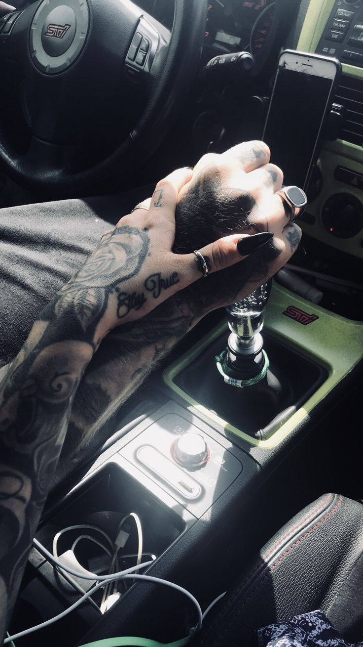 a man with tattoos on his arm sitting in a car