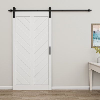 an empty room with a white door and black hardware on the sliding barn door,