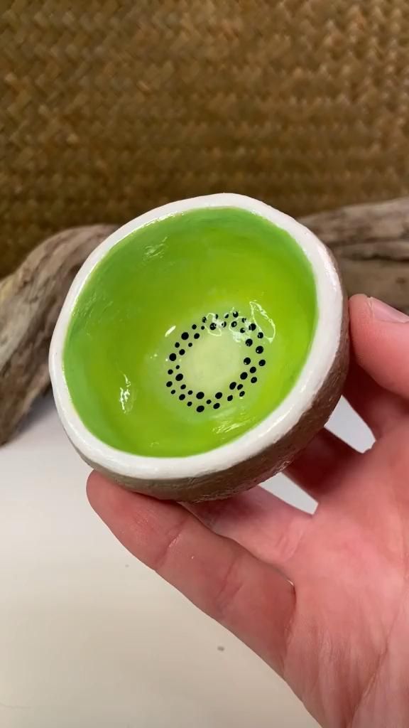 a person is holding a small bowl with green liquid in it that looks like a kiwi