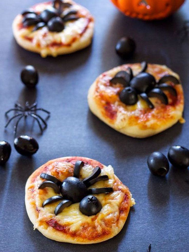 small pizzas decorated with black olives and spider decorations