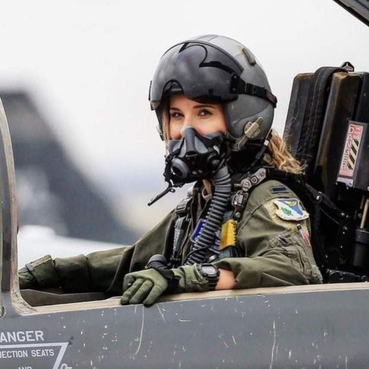 a female fighter pilot sitting in the cockpit of an airplane