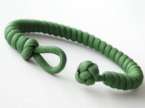 a green rope bracelet with two knoted ends on a white surface, one in the shape of an o - ring