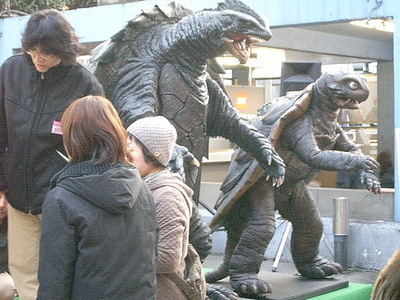 people are looking at statues of godzillas on display