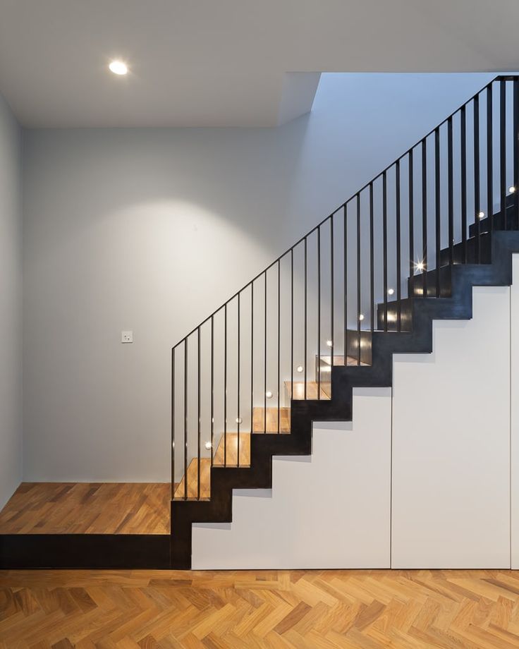 an empty room with a staircase leading to the top floor and lights on the wall