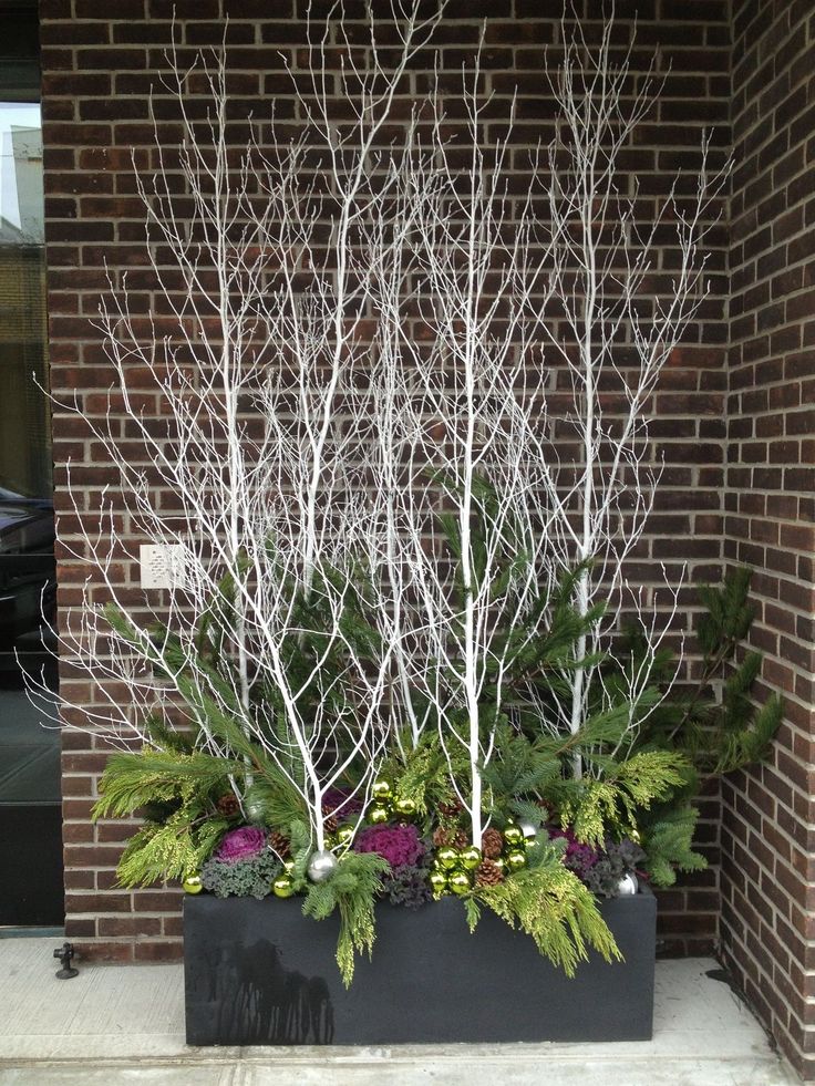 two metal planters filled with plants next to a brick building