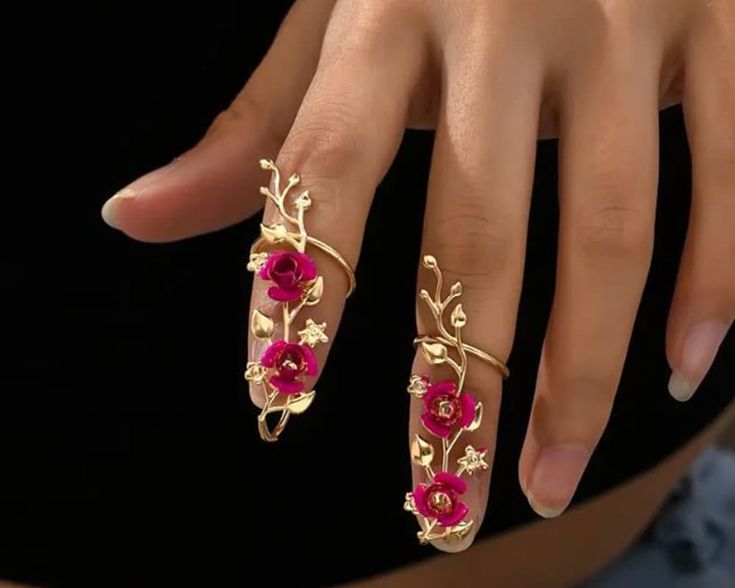 a woman's hand with two gold rings on it and pink flowers in the middle