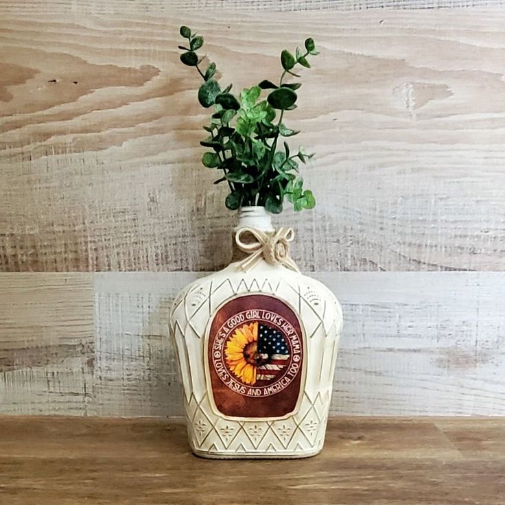 a bottle with some plants in it on a wooden table next to a wood wall