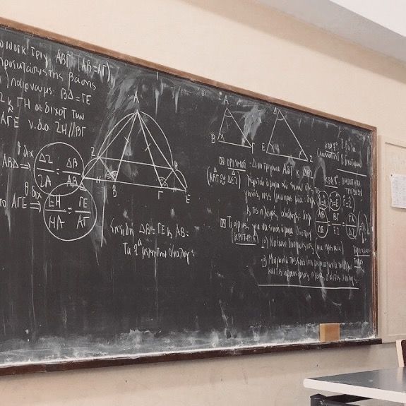 a blackboard with some writing on it in a classroom area next to two desks