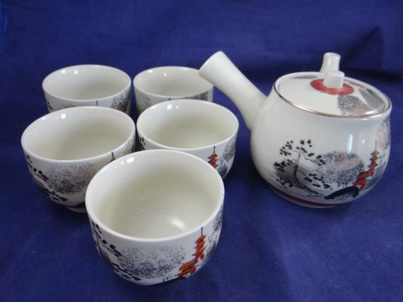 four cups and a teapot with designs on them