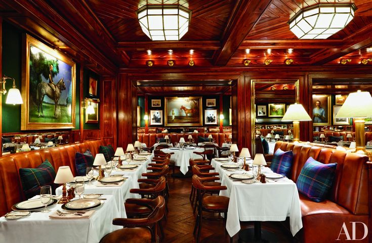 a dining room with wooden walls and tables covered in white tablecloths, brown leather seats