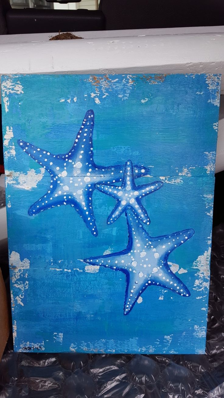 two starfishs are painted on a piece of wood with white paint and blue background