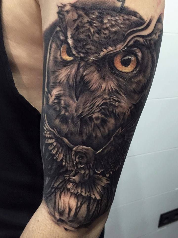 an owl tattoo on the arm with orange eyes and big ears is shown in black and grey