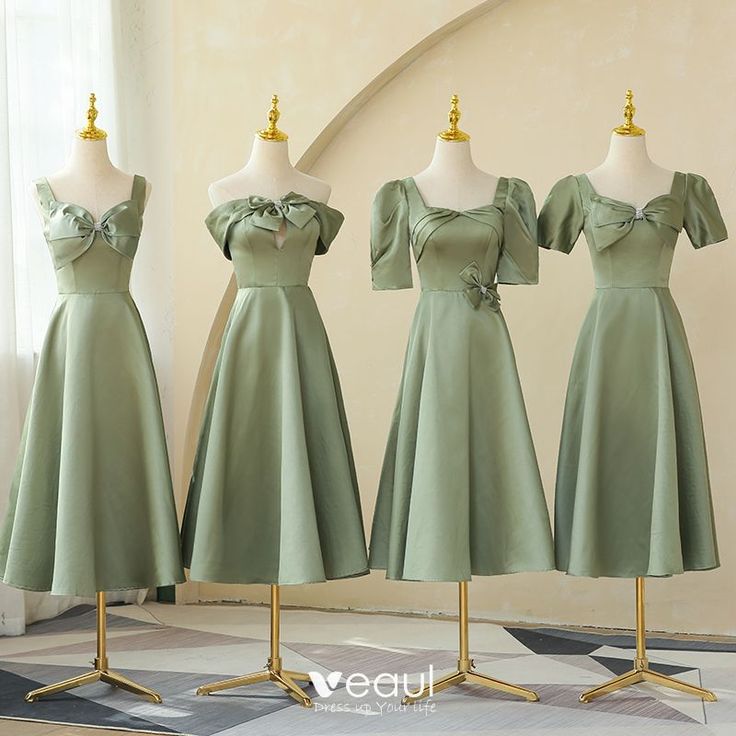 three green dresses on mannequins in front of a white wall and window