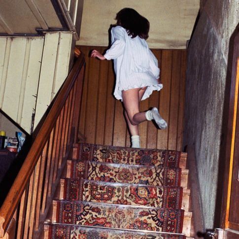 a woman in white shirt and skirt walking down stairs