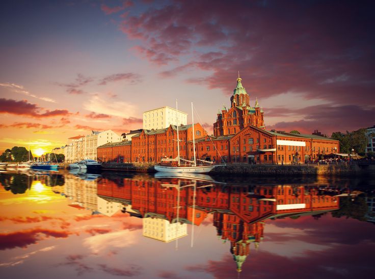 the sun is setting over an old building and boats are in the water near it