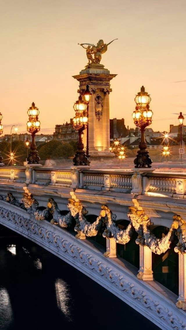 the bridge is lit up at night with street lamps on each side and an angel statue in the middle