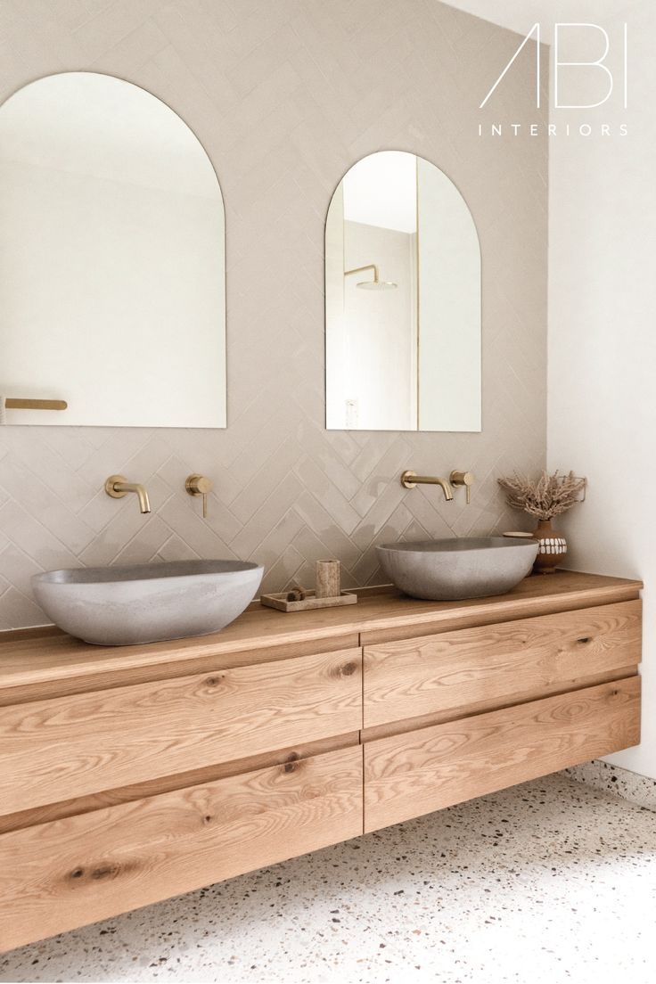 there are two sinks in the bathroom with mirrors on the wall above them and an oval mirror