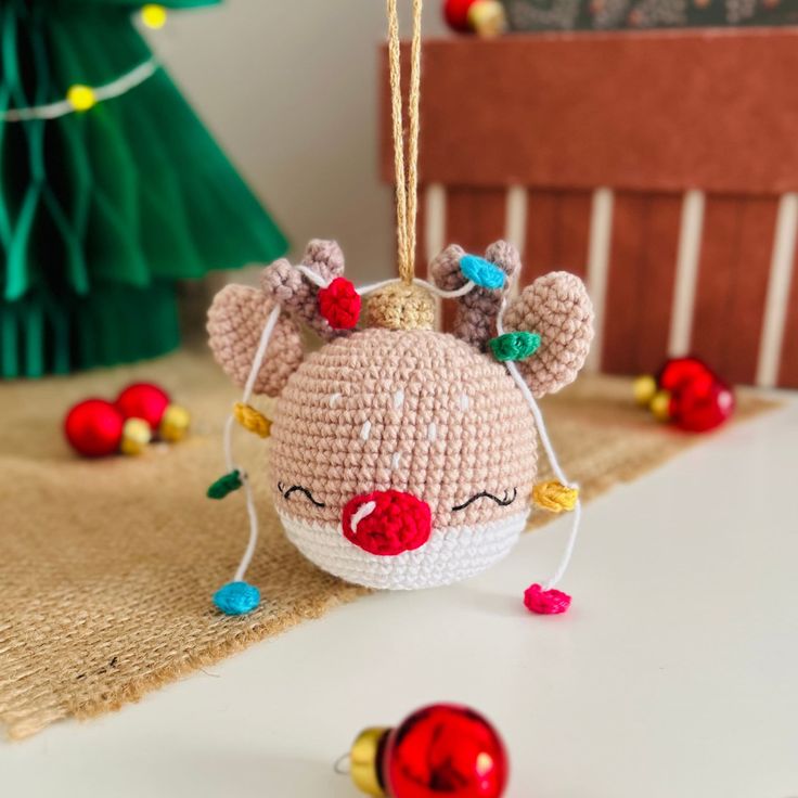 a crocheted christmas ornament hanging from a string on top of a table