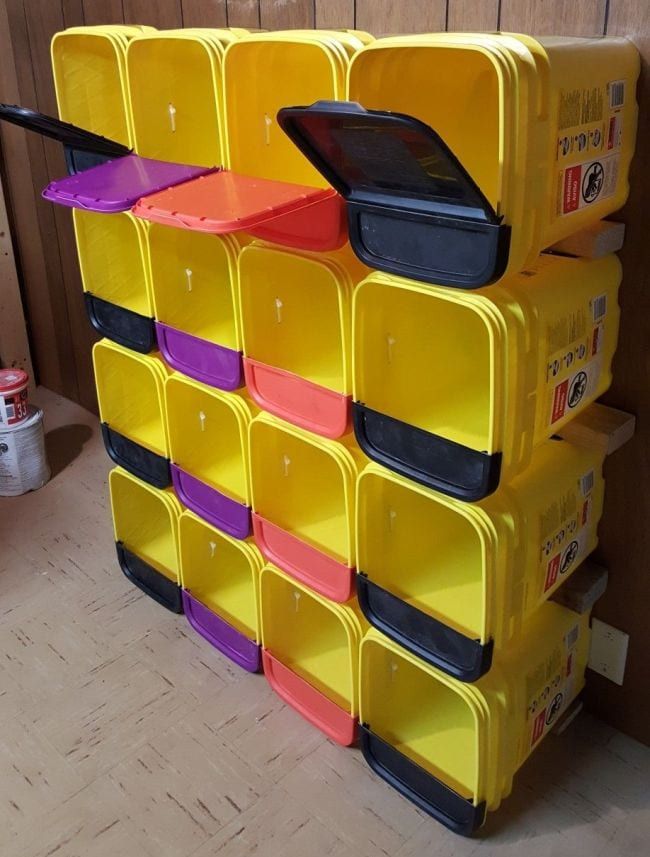 several yellow bins stacked on top of each other in front of a wooden wall