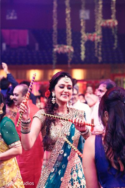 a woman in a blue and green sari holding an instrument while standing next to other people