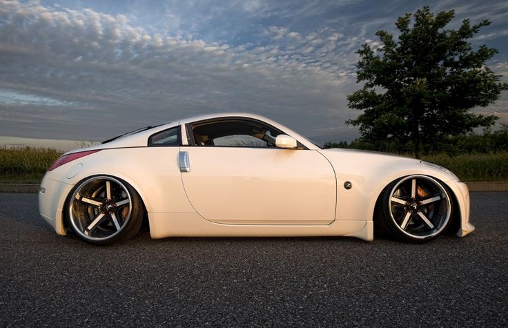 a white sports car parked on the side of the road with trees in the background