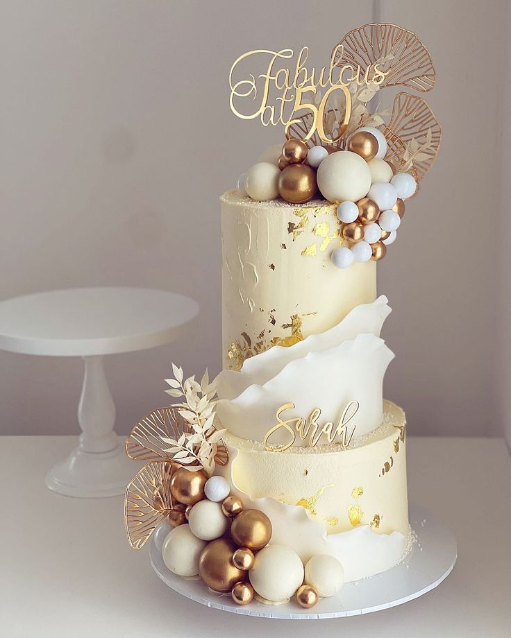 a three tiered cake with gold and white decorations