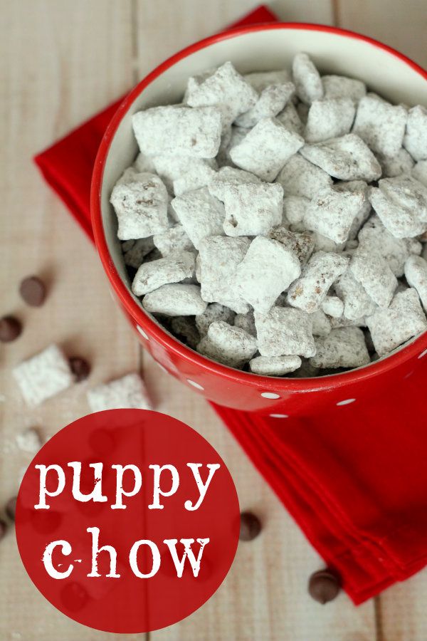 a red bowl filled with puppy chow on top of a wooden table next to chocolate chips