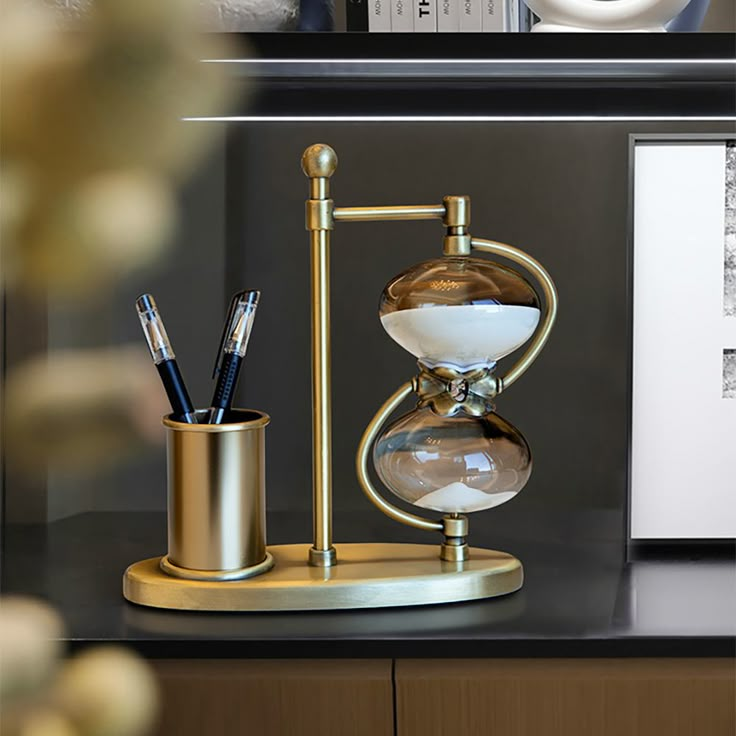 an hourglass and pen holder on a desk