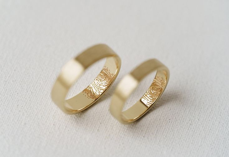 two gold wedding rings sitting next to each other