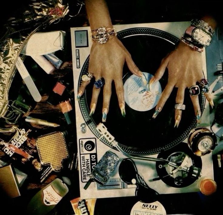 two hands on top of a record player surrounded by assorted jewelry and other items